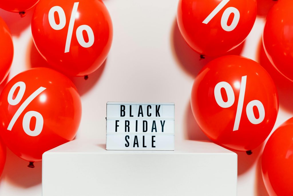Red balloons with percentage symbols flank a Black Friday Sale sign, creating a festive shopping atmosphere.